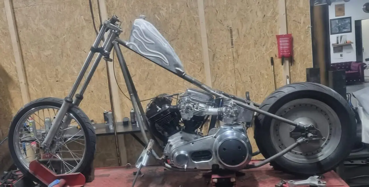 Custom chopper met blauw frame en gepolijst blok in de werkplaats