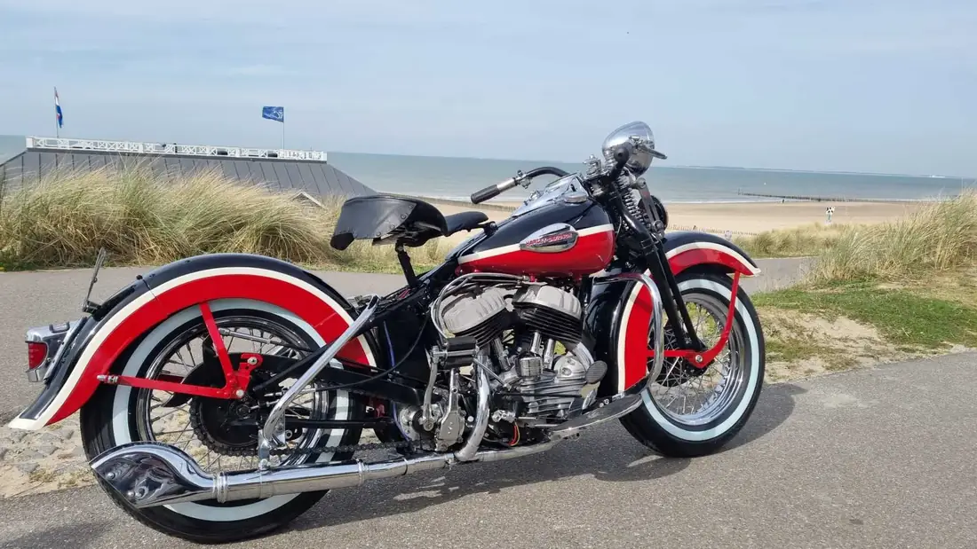 Gerestaureerde klassieke Harley-Davidson met witte banden aan de kust